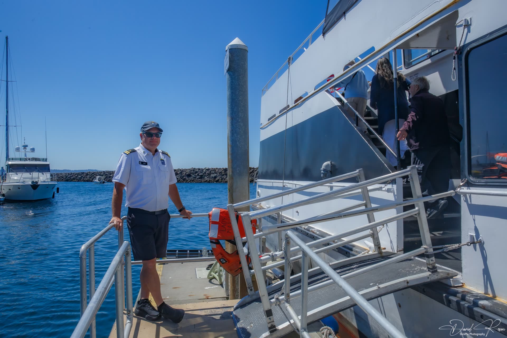 A crew member stands near the gangway as passengers board.