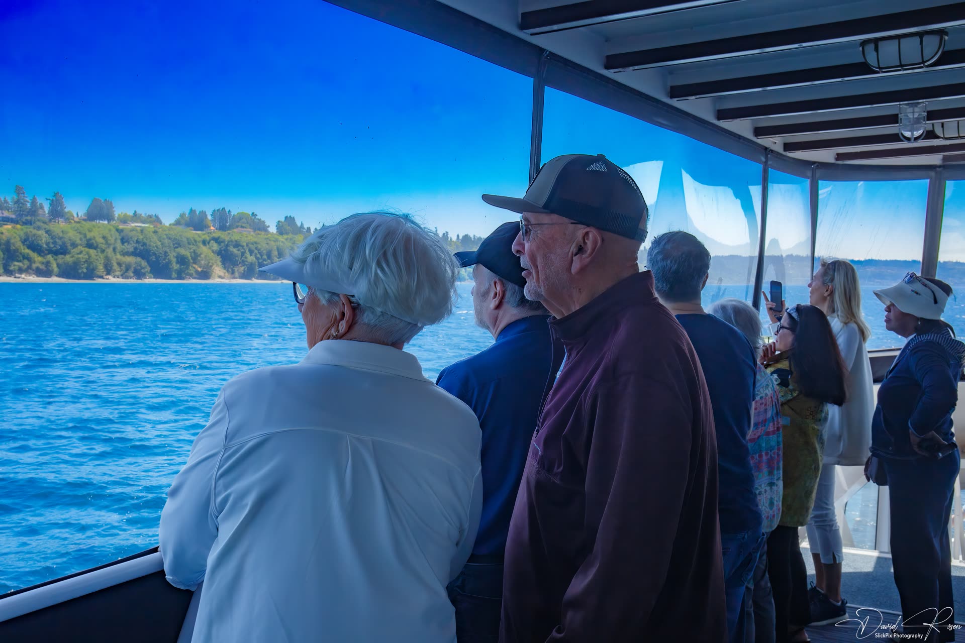 Passengers stand near the windows and look toward the Puget Sound shoreline.