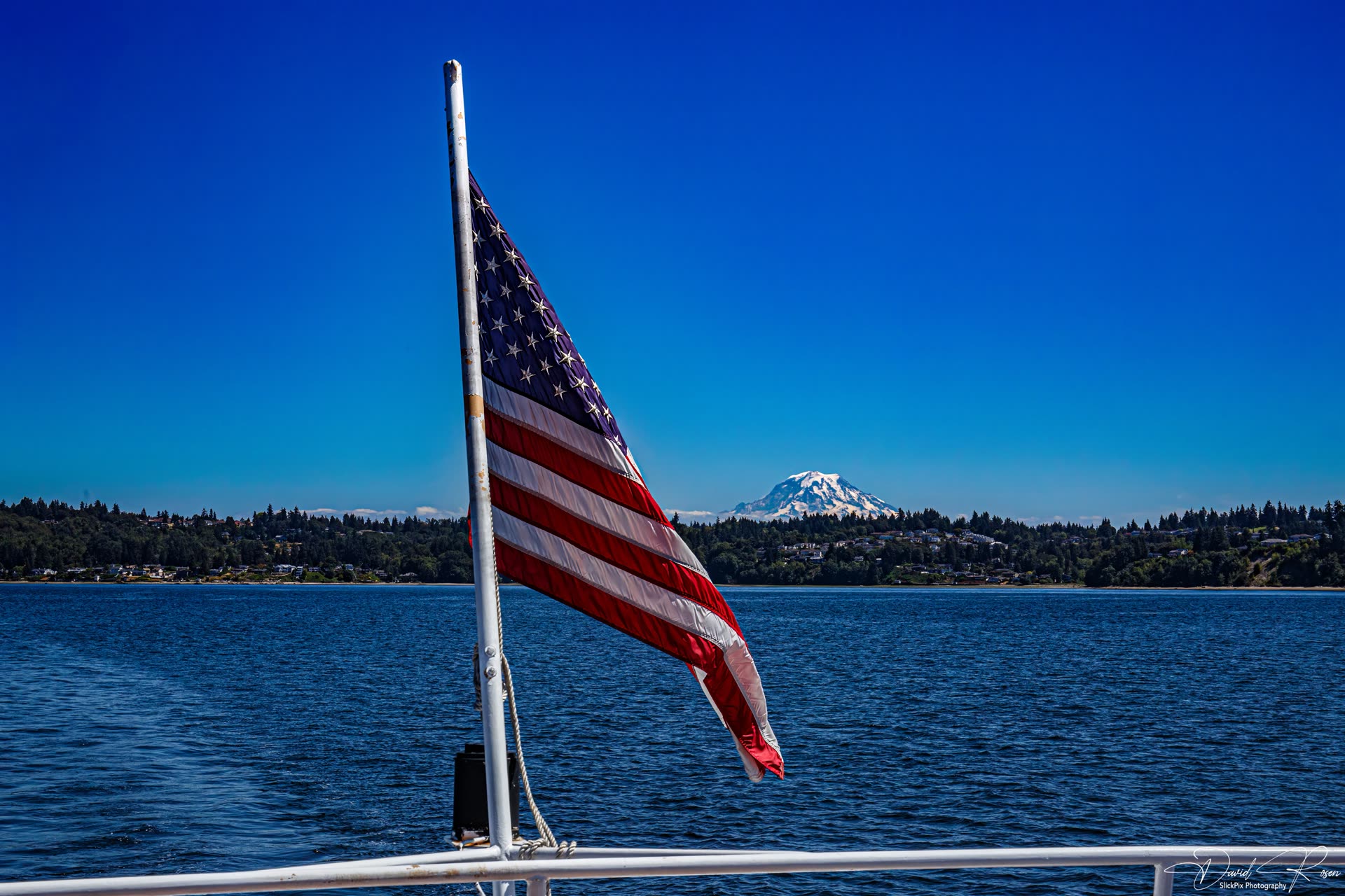 American flag on the vessel with Mount Rainier visible across Puget Sound.