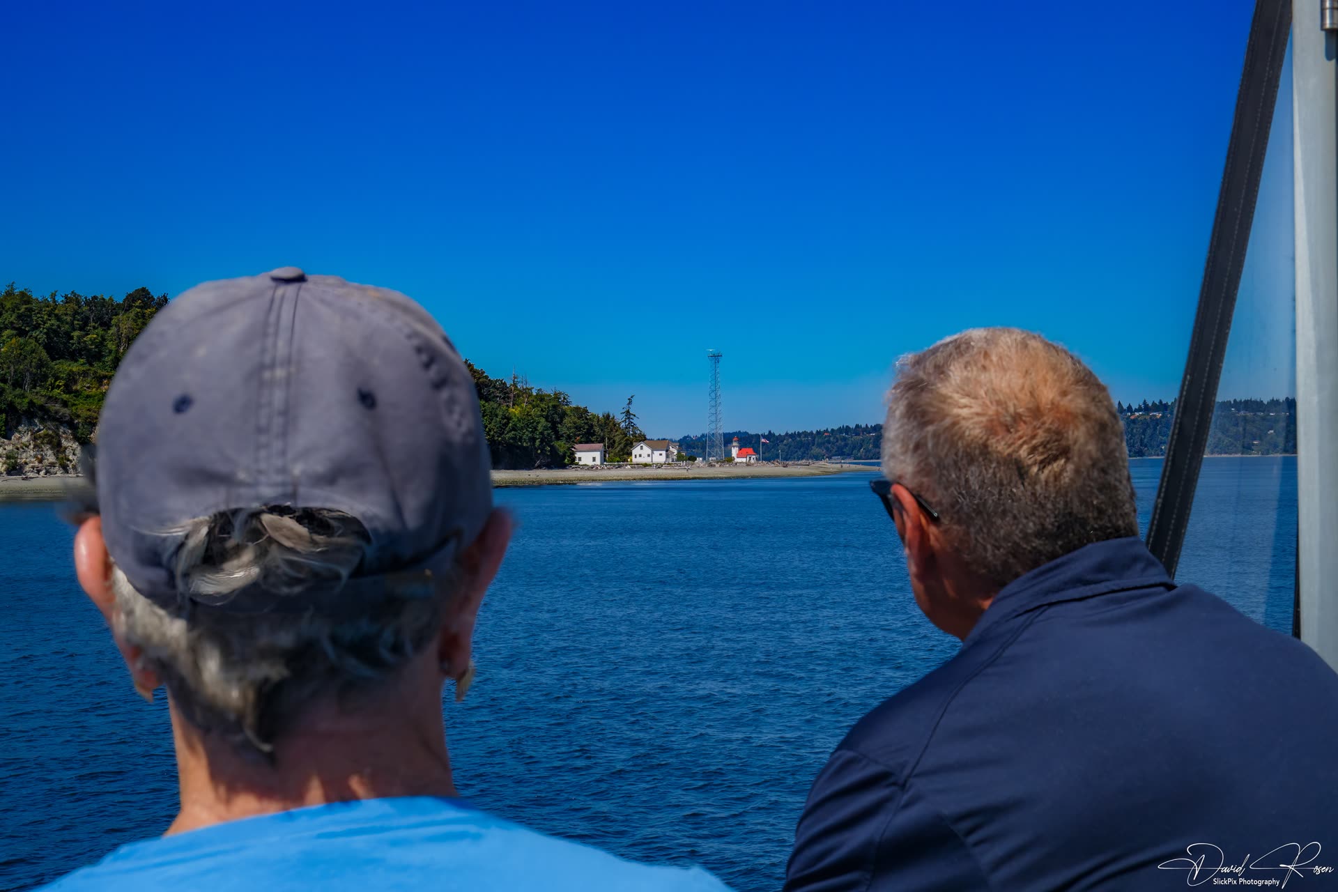 Passengers look through the cabin windows toward the shoreline.